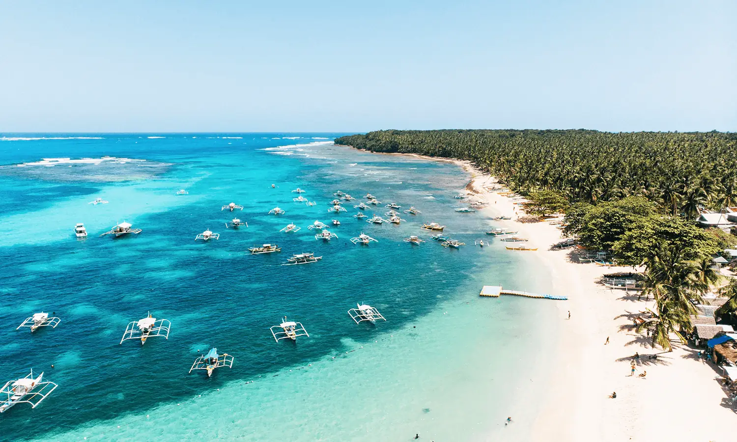Daku Island beach with palm trees and local eateries